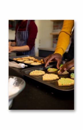 Midsection of diverse couple preparing christmas cookies in kitchen, copy space