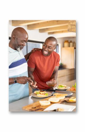 African American father and son preparing sandwiches together in modern kitchen