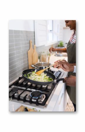 Cooking together, couple preparing meal with frying pan and wooden spoon in kitchen, copy space