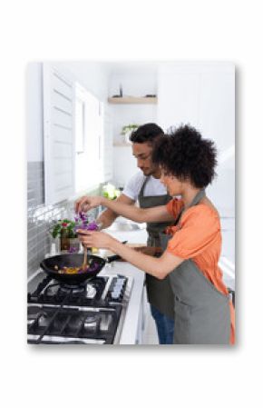 Cooking together, couple preparing meal in modern kitchen wearing aprons