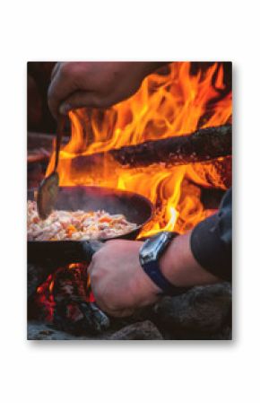 The man cooking food on a fire.
