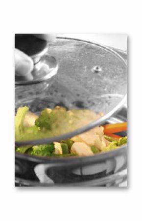 Steaming vegetables / Cooking vegetables in a steamer. Man removing lid.