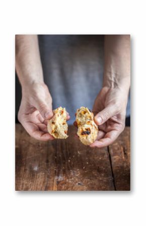 Cuoco spezza del pane con bacche di goji su un tavolo di legno scuro