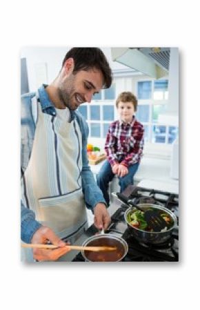 Boy looking while father cooking food