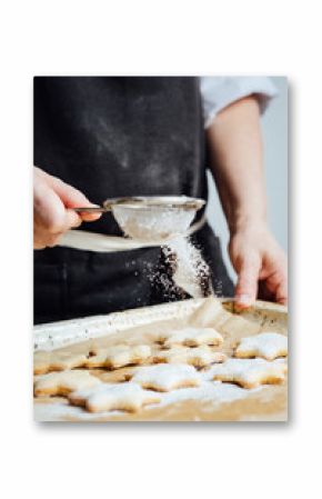 Hands of cook adding powdered sugar to cookies as a topping