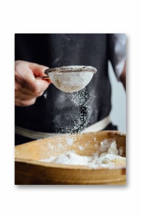Person adds flour to a pastry through the strainer. Vertical studio shot.