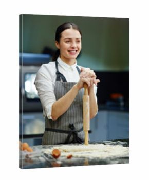 Smiling woman with rolling-pin making dough in the kitchen