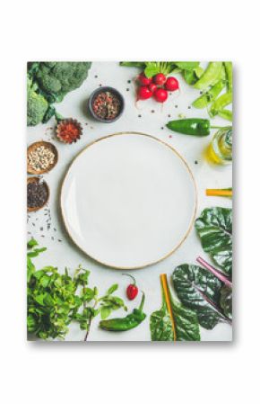 Fresh raw greens, unprocessed vegetables and grains over light grey marble kitchen countertop, wtite plate in center, top view, copy space. Healthy, clean eating, vegan, detox, dieting food concept