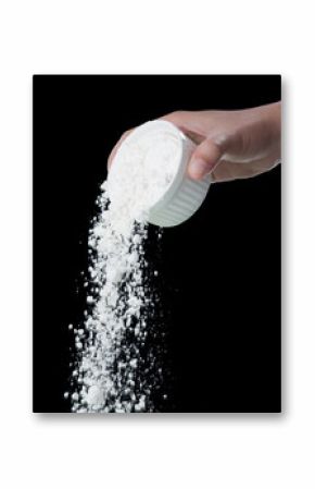 Pouring flour from the measure bowl on black background