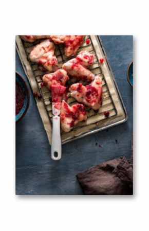 Raw chicken legs in cranberry sauce on dark stone surface