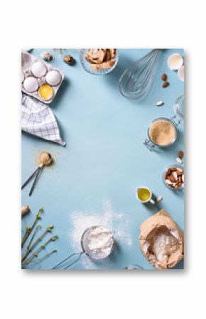 Bakery background frame. Fresh cooking ingredients - egg, flour, sugar, butter, nuts over blue background. Spring cooking theme. Top view, copy space.