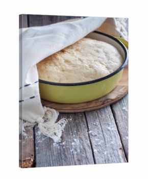 Yeast dough raw in a bowl on a wooden table. Country style, selective focus