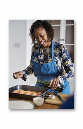 Woman adding spices and herb to raw salmon