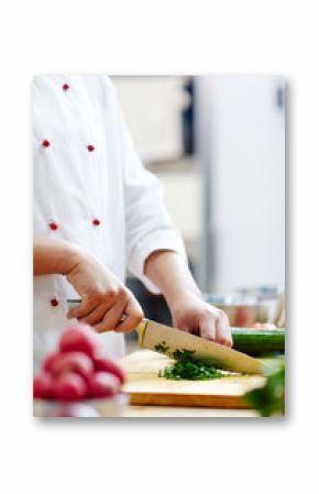 Chef in uniform shredding green aromatic herbs for soup