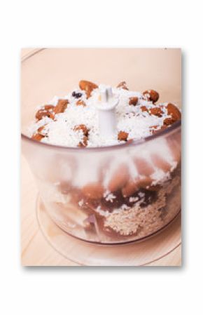 A mixture of chopped nuts, dates with coconut chips and almonds in a food processor for cooking energy bites.