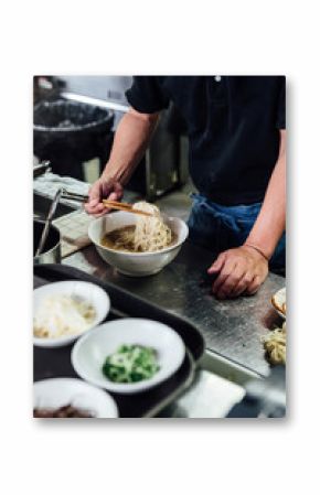 Chef making Hakata style Chashu Ramen by holding ramen noodle in Shio soup with chopsticks.