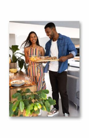 Couple joyfully preparing dinner table with fresh bread and snacks at home