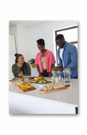 African American family preparing and enjoying meal together in modern kitchen