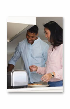 Couple in kitchen making breakfast together, smiling and enjoying morning routine
