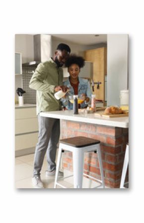 Preparing breakfast together in modern kitchen, African American couple smiling warmly