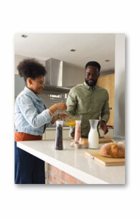 Couple in kitchen preparing meal together, smiling and enjoying cooking time