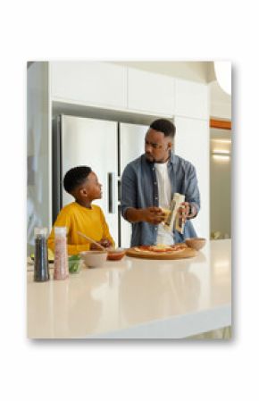 In kitchen, father and son making homemade pizza, spending quality bonding time