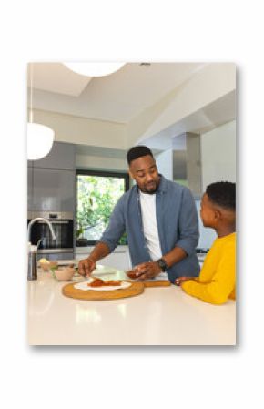 Father and son preparing pizza together in modern kitchen, enjoying family time