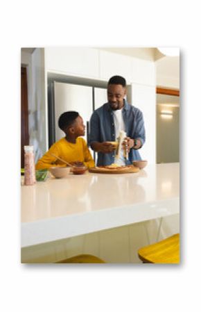 Father and son making pizza together in modern kitchen, enjoying family time