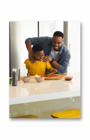 Father and son making pizza together in kitchen, sharing joyful moment