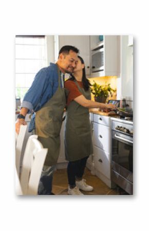 Cooking together in kitchen, mature couple sharing affectionate moment preparing meal
