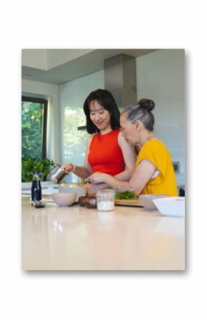 Cooking Chinese mother and daughter preparing eggs and asparagus at kitchen island, with bowls