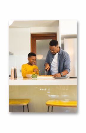 Father and son preparing pizza together in modern kitchen, enjoying family time