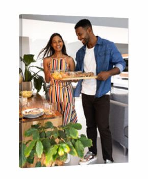 Couple joyfully preparing dinner table with fresh bread and snacks at home