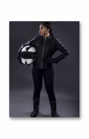 Black female motorcycle biker or race car driver or stuntwoman wearing leather racing suit and holding a protective helmet.  She is standing confidently in a studio