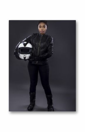 Black female motorcycle biker or race car driver or stuntwoman wearing leather racing suit and holding a protective helmet.  She is standing confidently in a studio