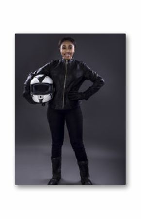 Black female motorcycle biker or race car driver or stuntwoman wearing leather racing suit and holding a protective helmet.  She is standing confidently in a studio