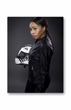 Black female motorcycle rider or race car driver wearing a racing helmet and leather jacket. Part of the gritty woman series, a competitive biker or racer getting ready for competition.