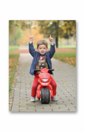 cute little biker on road with motorcycle. Young boy on toy motorcycle