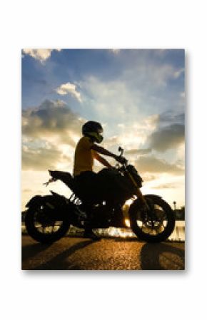 Silhouette biker with his motorbike beside the natural lake and beautiful sunset sky.