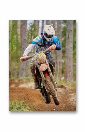 Motocross driver jumping with the bike at high speed on the race track