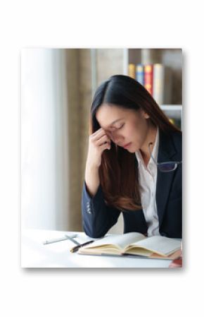 A female lawyer looking stressed while working in her office, holding glasses and touching her forehead.