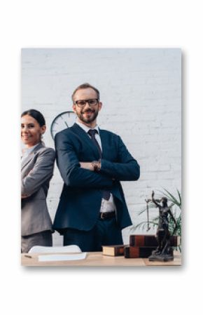 lawyers in suits standing with crossed arms and looking at camera in office