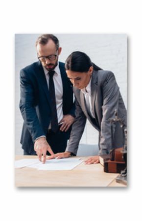 selective focus of bearded lawyer pointing with finger at document near businesswoman in office