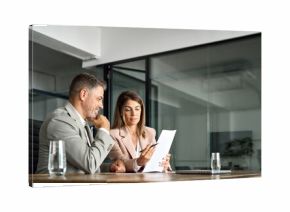 Two professional executives discussing financial accounting papers working with paperwork in office. Mature business woman and man managers holding legal corporate documents at meeting. Copy space.