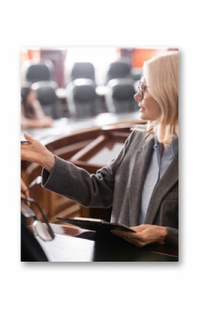 middle aged attorney pointing with hand near grey-haired judge in courtroom