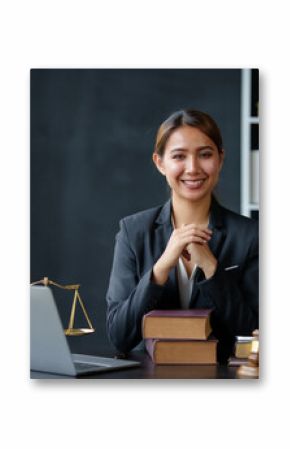 Beautiful Asian woman lawyer sitting at a table smiling happy with a laptop computer with law books hammer and scales hammer and scale.