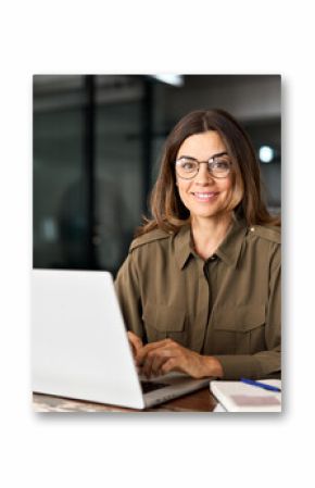 Happy smiling mature middle aged professional business woman investor manager executive or lawyer attorney adviser looking at camera at workplace working on laptop computer in office, portrait.