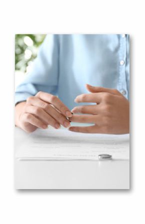 Young woman slipping ring off her finger at table, closeup. Concept of divorce