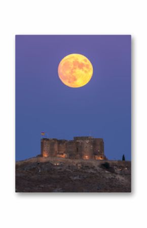 From below picturesque scenery of abandoned aged fortress on top of mountain illuminated by full Moon at night in Toledo