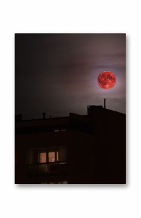 Red full moon in red color also called bloodmoon on the background of building.